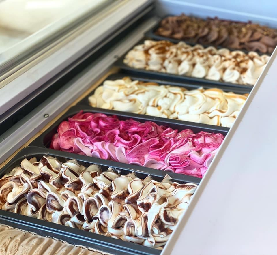 A vibrant display case filled with assorted gelato flavors at Pecorino, filled with colorful ice cream options